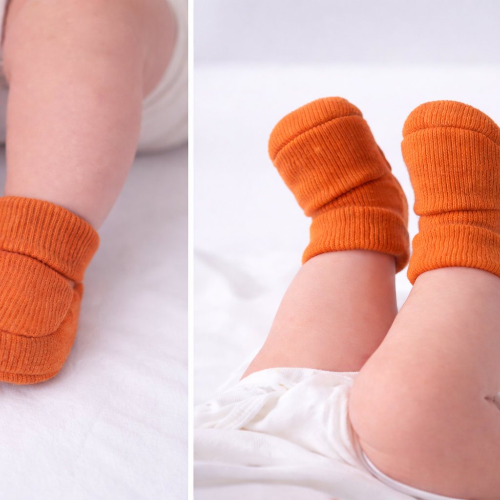 Baby wearing organic cotton bronze baby booties on a white background