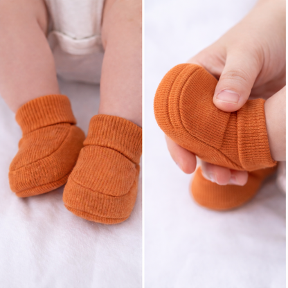 Close-up of organic cotton bronze baby booties worn by a baby
