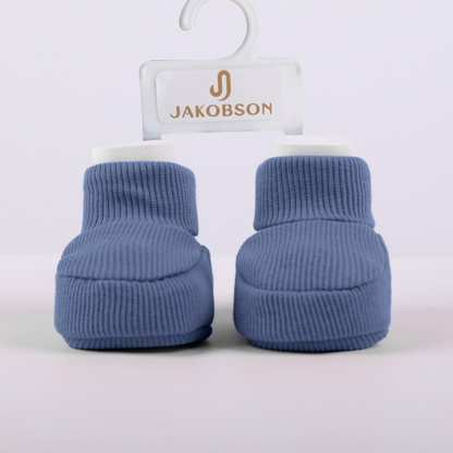 Organic cotton baby booties in navy blue displayed on a Jakobson branded hanger for newborn comfort