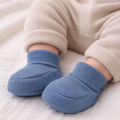 Baby wearing organic cotton navy blue baby booties with soft beige pants