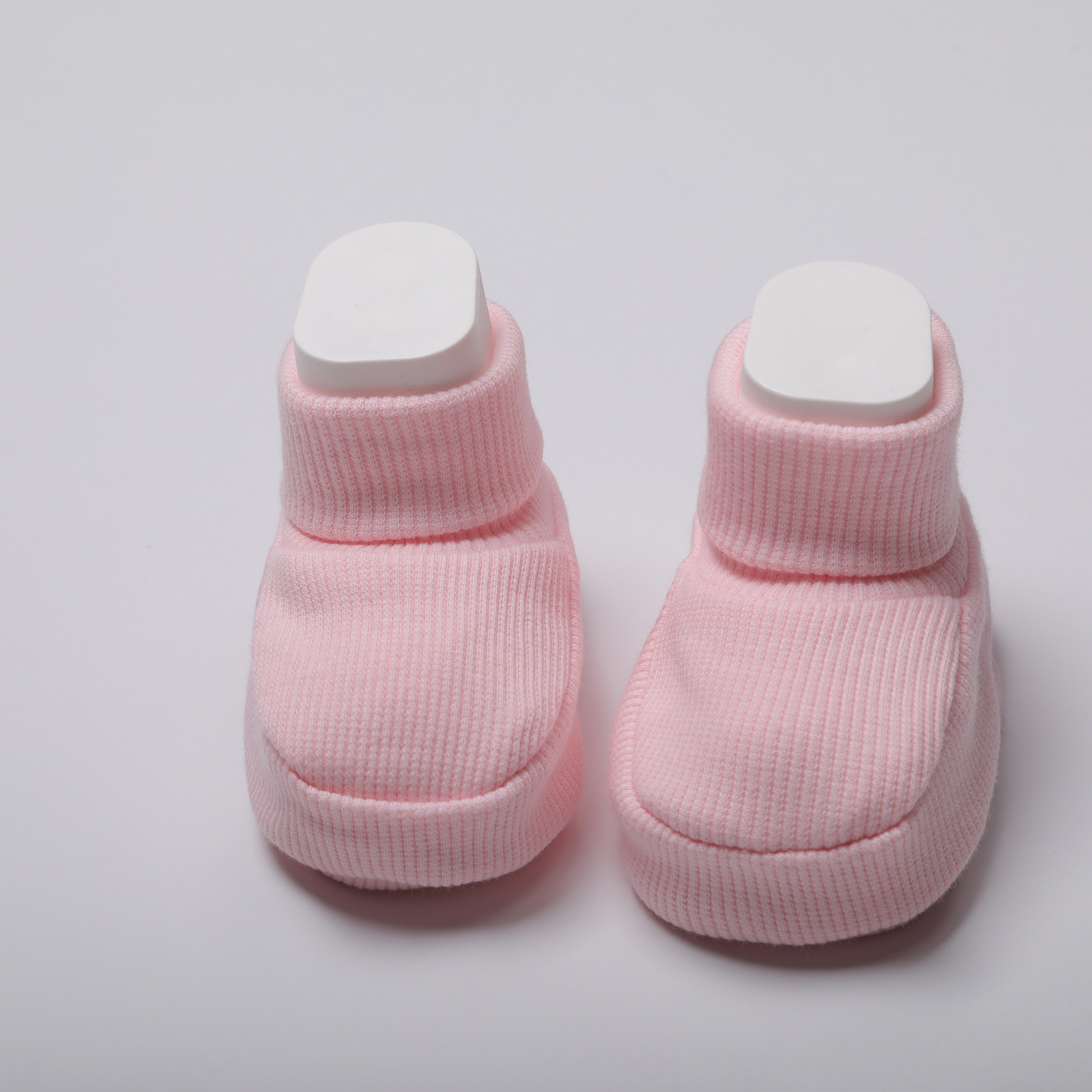 Organic cotton baby booties in pink on a light gray background for newborn comfort