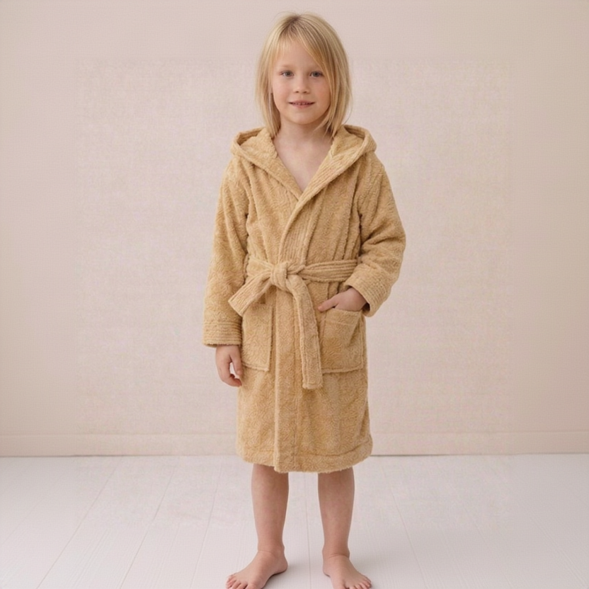 Child wearing a beige hooded robe on a plain background