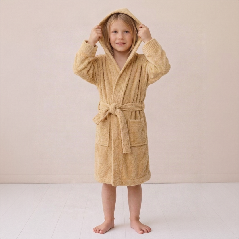 Child wearing a beige robe on a plain background