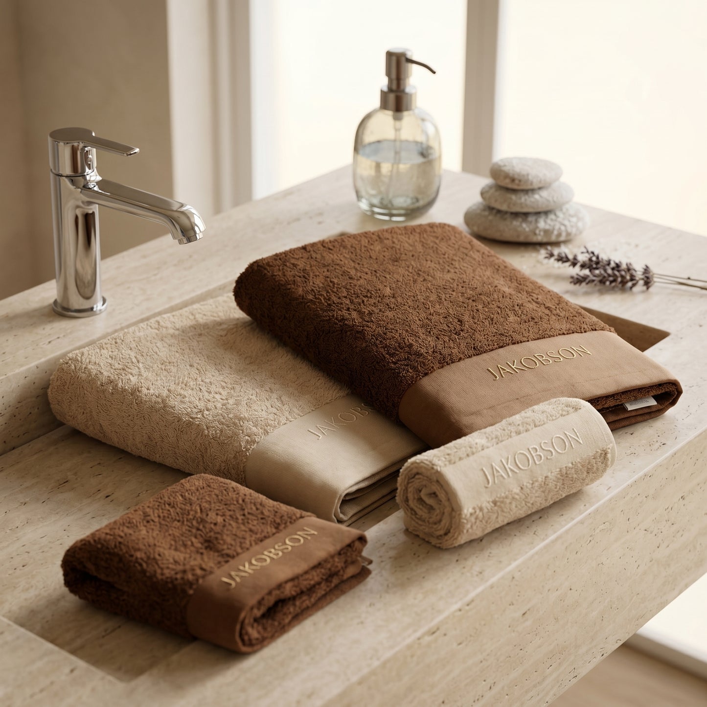 4-piece organic cotton towel set in beige and cinnamon displayed on a bathroom counter with Jakobson branding
