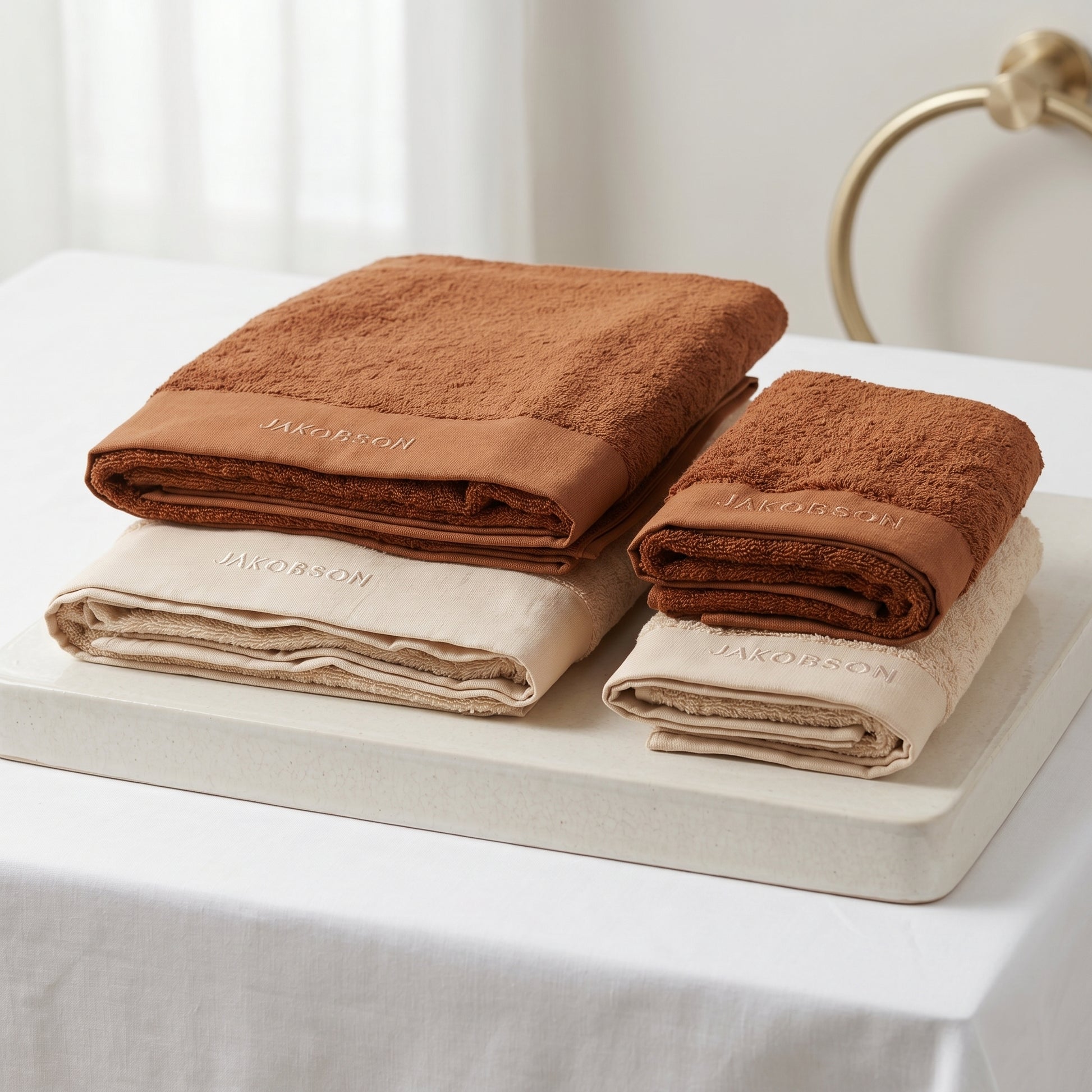 4-piece organic cotton towel set in beige and cinnamon with Jakobson branding made from soft terry fabric