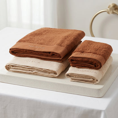 4-piece organic cotton towel set in beige and cinnamon with Jakobson branding made from soft terry fabric