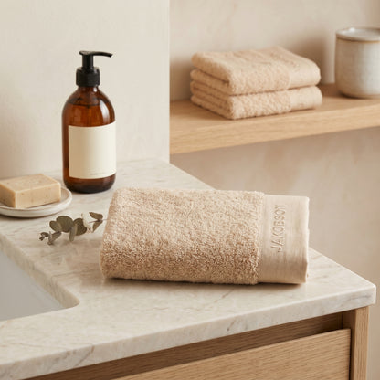 Organic cotton terry bath towel in beige made from 100% organic cotton styled with bath accessories