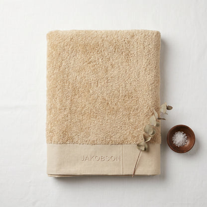 Organic cotton terry bath towel in beige with Jakobson branding made from 100% organic cotton