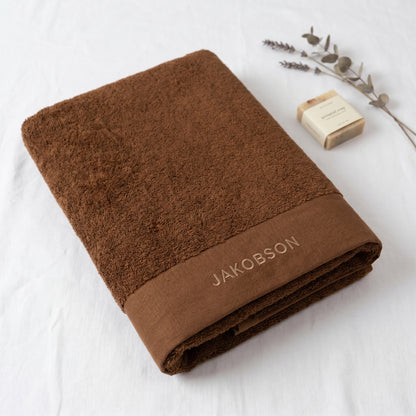 Organic cotton terry bath towel in cinnamon with Jakobson branding made from 100% organic cotton